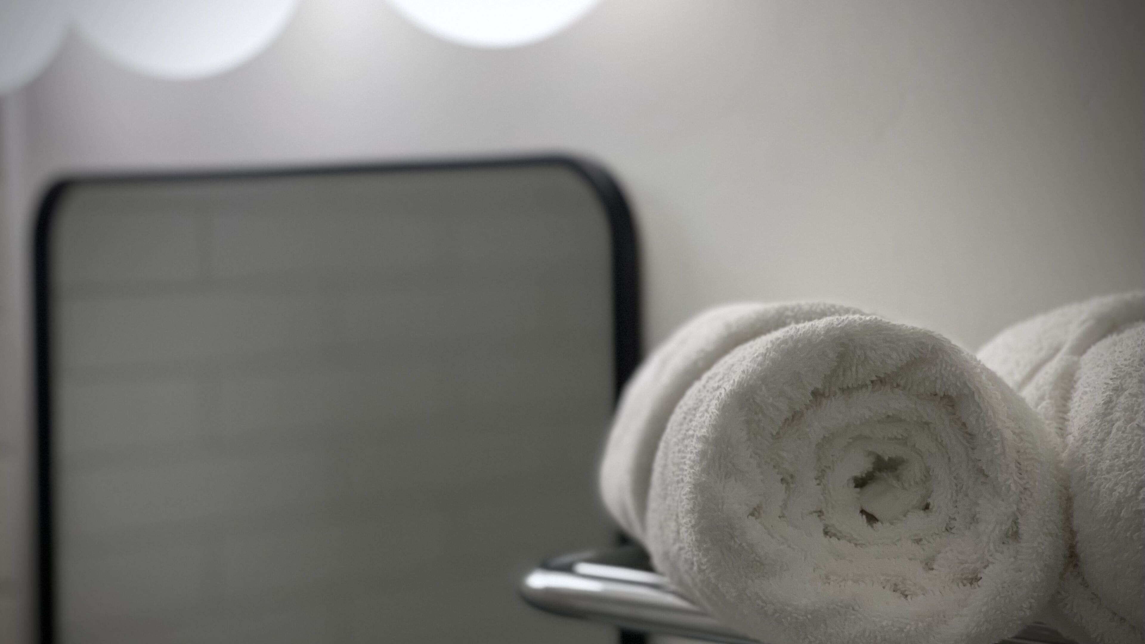 A bathroom with a towel rack holding rolled towels.