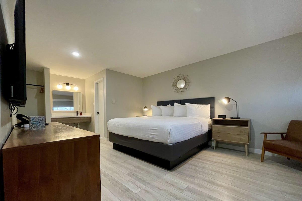 Une chambre moderne avec un grand lit, des tables de chevet, un bureau et un téléviseur.