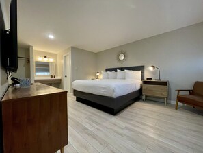A modern bedroom with a large bed, bedside tables, a desk, and a TV.