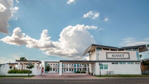 Un motel llamado 'Arizona Sunset Inn' con un diseño arquitectónico moderno, que presenta una entrada destacada y una vista despejada del cielo.
