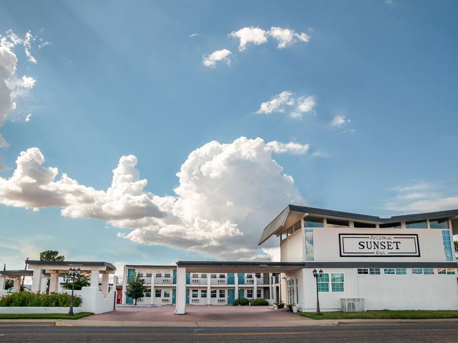 A motel named 'Arizona Sunset Inn' with a modern architectural design, featuring a prominent entrance and a clear view of the sky.