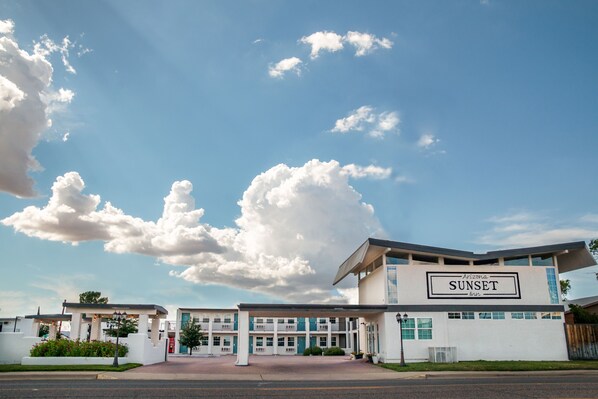 Un motel llamado 'Arizona Sunset Inn' con un diseño arquitectónico moderno, que presenta una entrada destacada y una vista despejada del cielo.