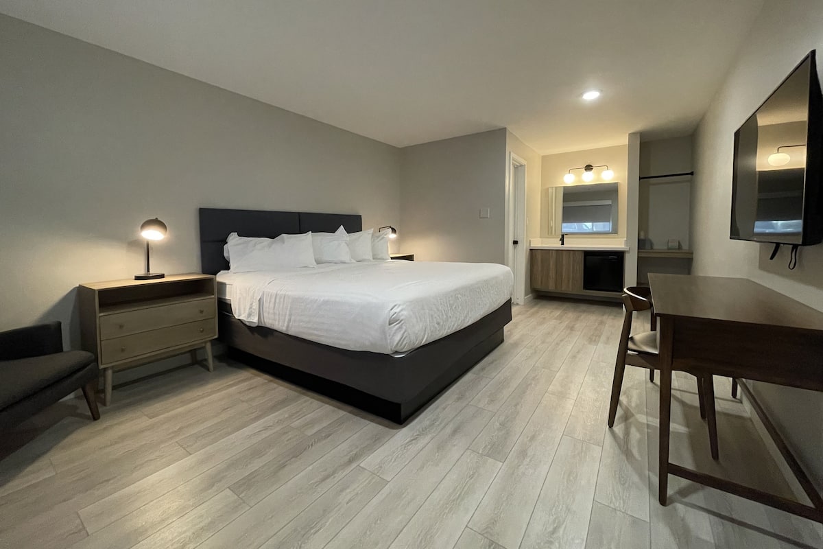 Une chambre moderne avec un grand lit, des tables de chevet, un bureau et un miroir.
