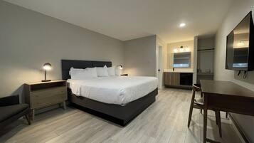 A modern bedroom with a large bed, bedside tables, a desk, and a mirror.