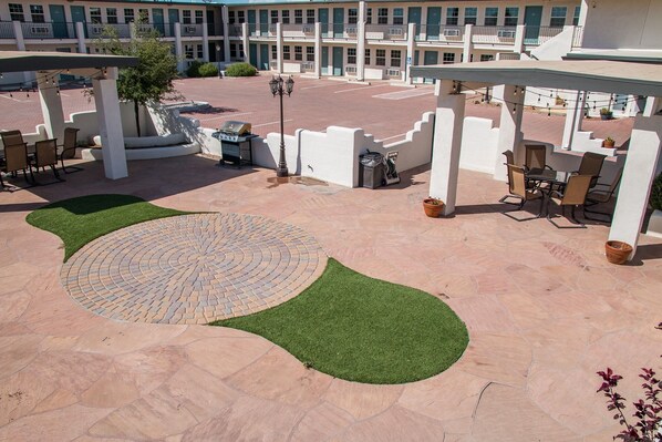 Un patio al aire libre con arreglos de asientos y una zona pavimentada circular con césped.