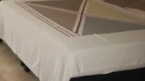 Een slaapkamer met een bed, een kledingkast, een nachtkastje met lamp en een raam met gordijnen.