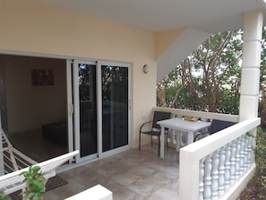 A balcony with a white railing, a table with chairs, and a sliding glass door leading to an indoor area. - Wayaca Mini Resort (Jan Thiel)