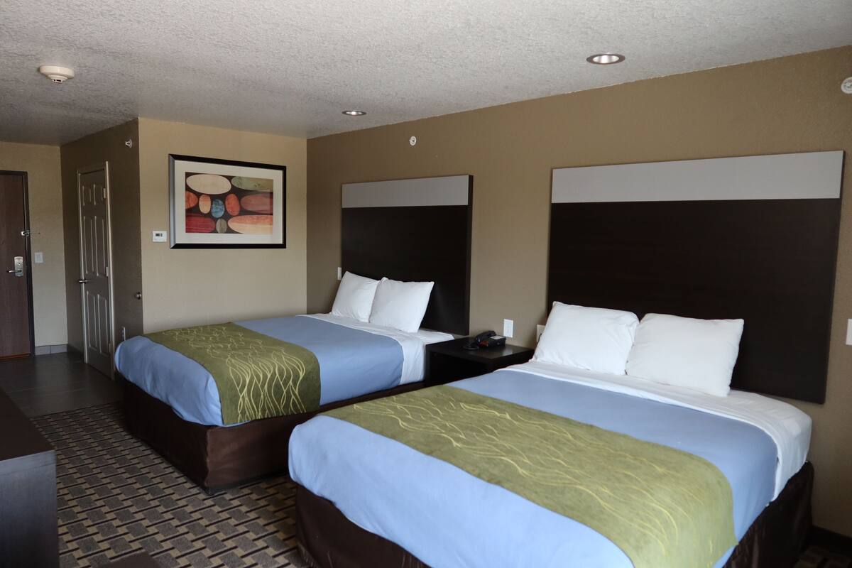 Ein Hotelzimmer mit zwei Betten, einem Bild an der Wand und einer Tür.