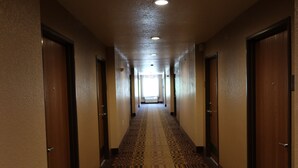 Ein Hotelgang mit Teppichböden, Holztüren und einer Decke mit eingelassenen Leuchten.