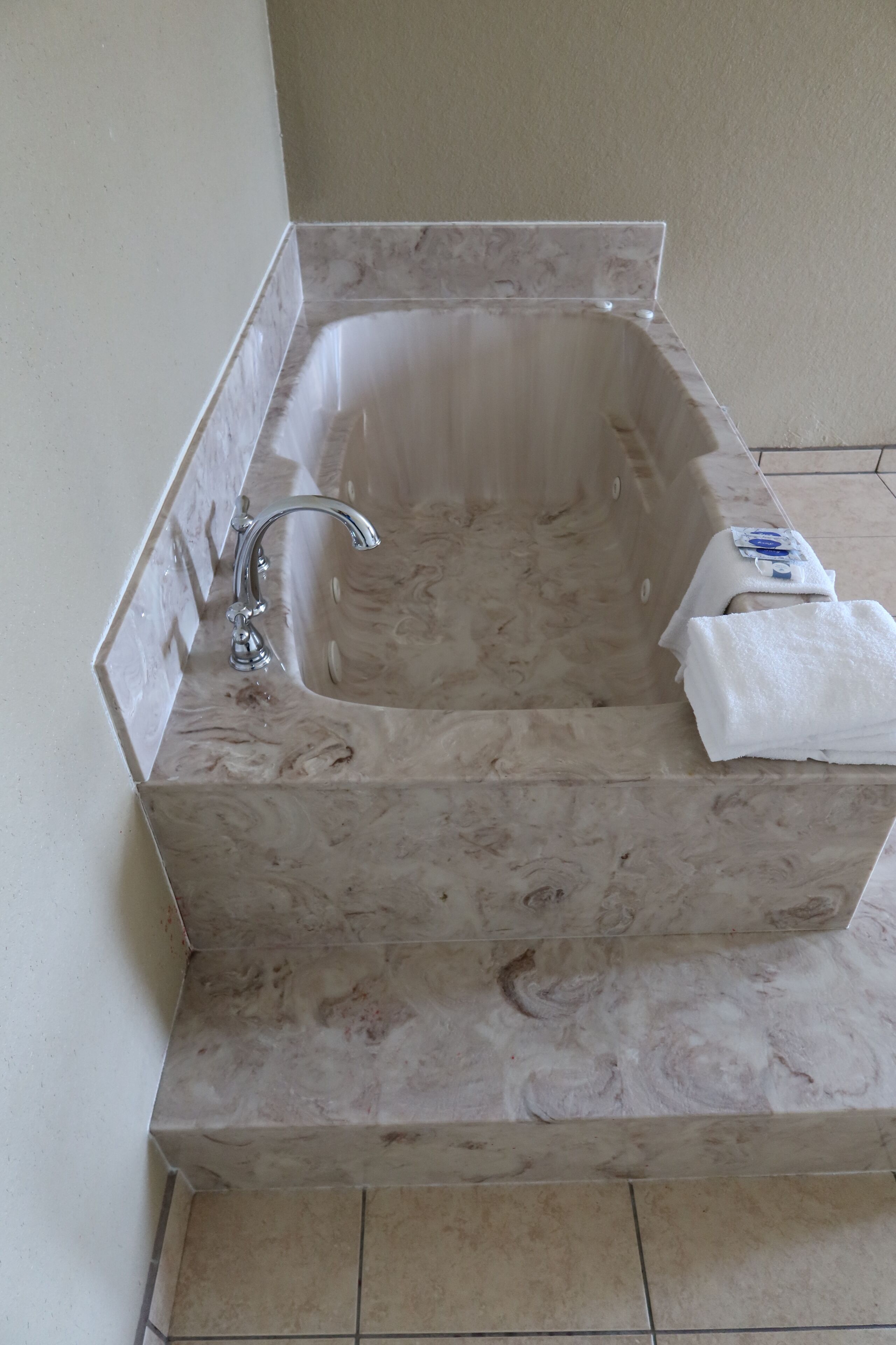 A bathroom with a marble sink, a single faucet, and a towel on the counter.