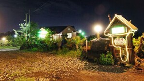 Una vista nocturna de un edificio con señalización iluminada y un jardín bien cuidado.