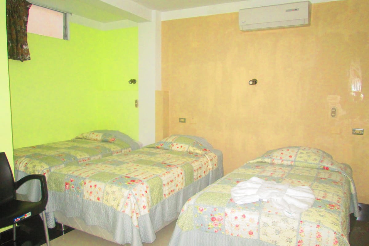 Una habitación de hotel con dos camas individuales, una silla y una mesita.