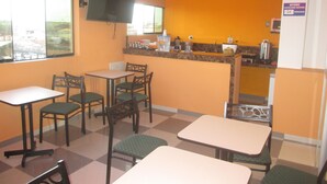 A restaurant with a kitchen area, multiple tables and chairs, and a television mounted on the wall. - Ari's Hotel III (Iquitos)