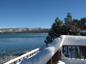 Ein mit Schnee bedeckter Deck mit Blick auf einen See und Berge im Hintergrund.