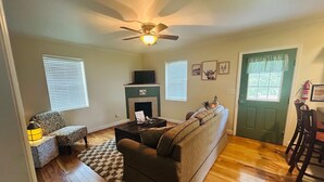 A living room with a fireplace, a ceiling fan, and a green door. - Mountain Cove Farms Resort (Chickamauga)