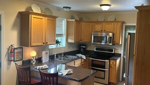 A kitchen with wooden cabinets, a stainless steel refrigerator, a microwave, an oven, and a coffee maker. - Mountain Cove Farms Resort (Chickamauga)