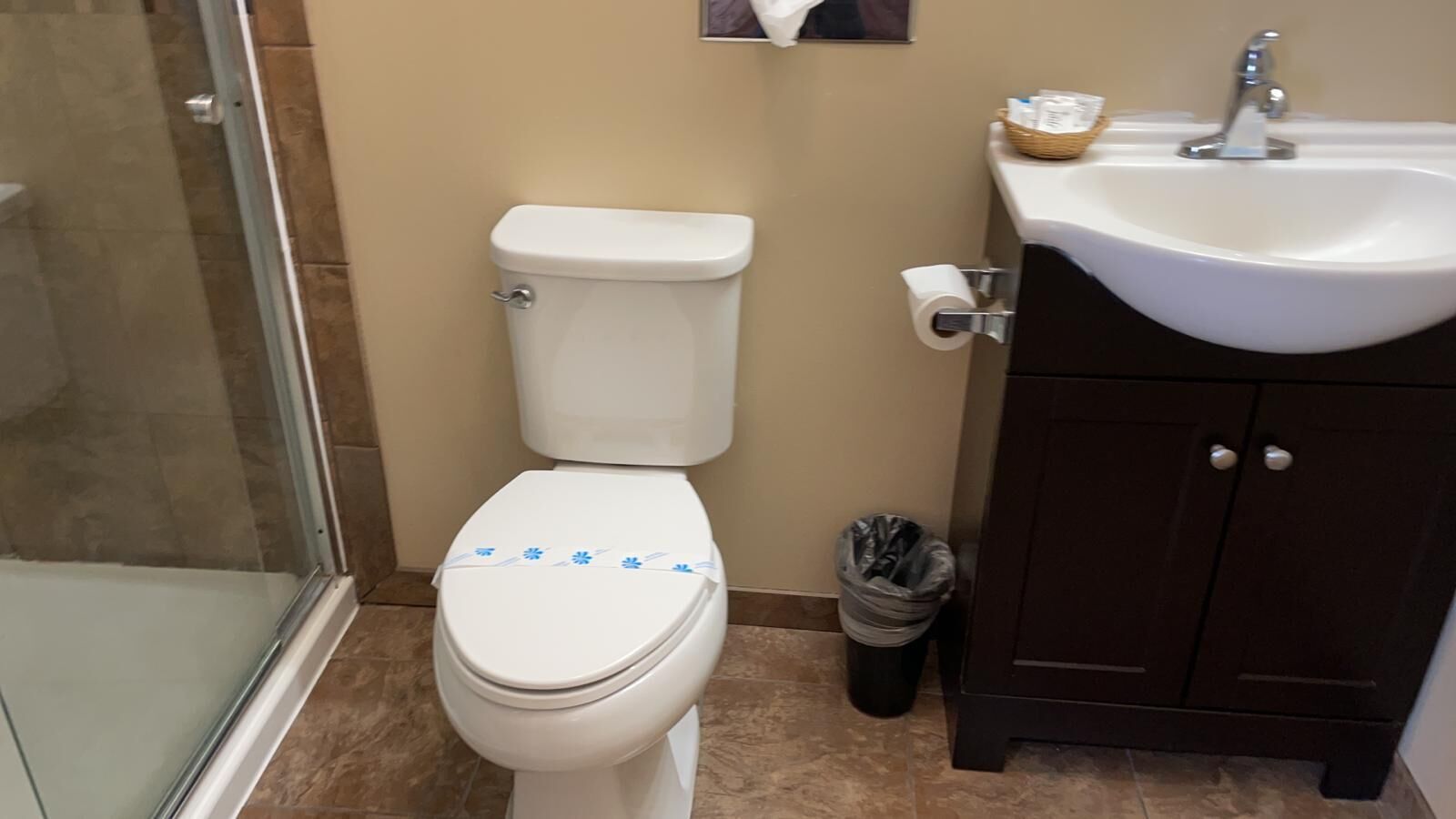 Un baño con inodoro, lavamanos y un cubo de basura.