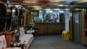 A hotel lobby with a curved staircase, a reception desk, and floral-patterned seating. - Hotel La Joya (La Paz)