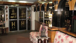 A hotel lobby with wooden paneling, a reception desk, and a seating area with floral upholstery. - Hotel La Joya (La Paz)