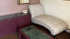 A bedroom with a bed, a dresser, a vanity, a mirror, and a painting on the wall. - Itascan Motel (Grand Rapids)