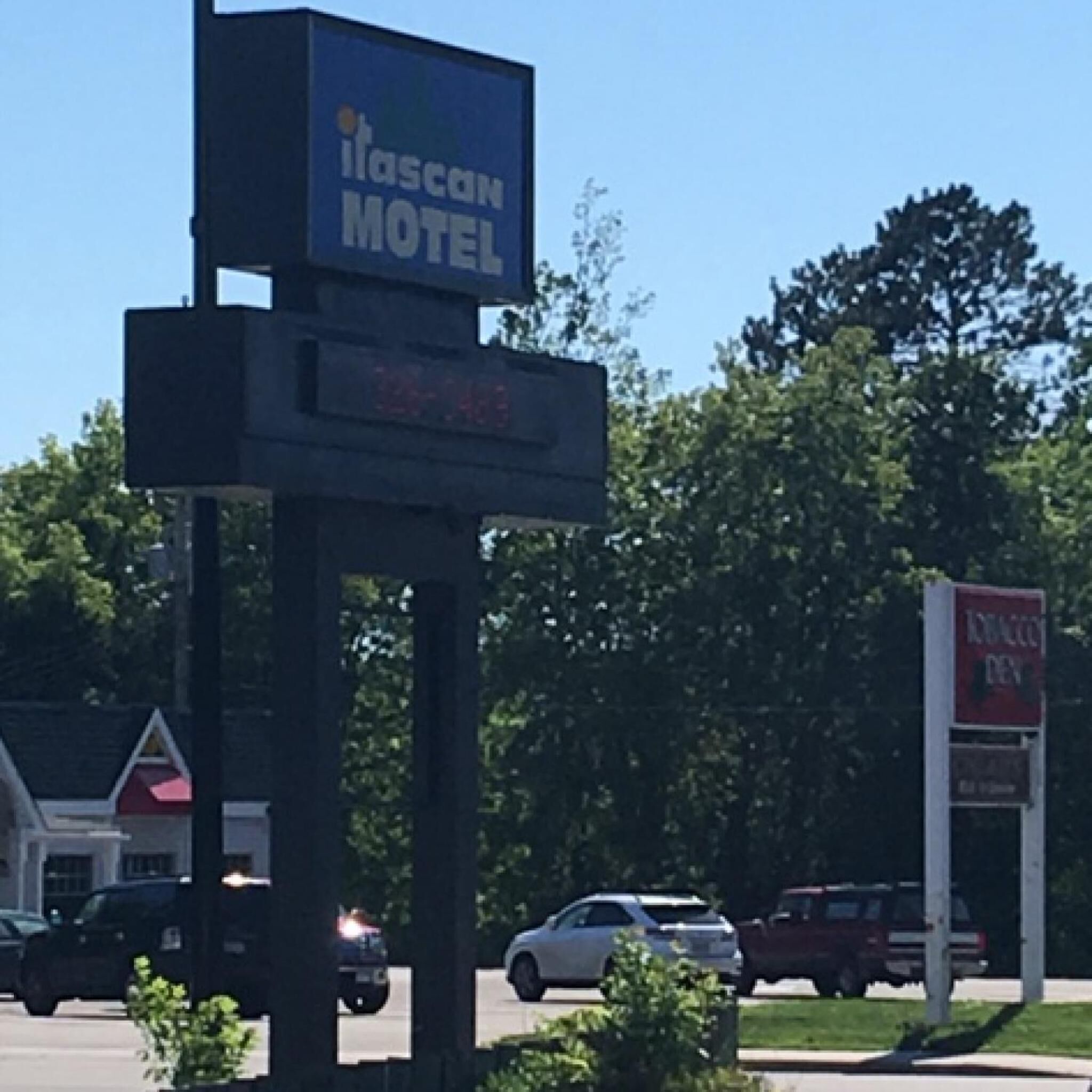 Señal de motel con el nombre 'Itasca Motel' y un panel digital que indica 'Abierto las 24 horas'.