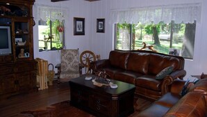 A living room with a brown leather sofa, a wooden coffee table, and a wooden cabinet.