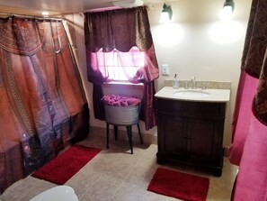 A bathroom with a sink, a toilet, and a shower area with curtains. - Lonesome Dove Guest Ranch (Kalispell)
