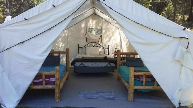 A tent with two wooden beds and a central sleeping area.