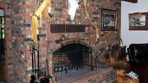 A brick fireplace with a stone hearth, surrounded by various decorative items and mounted animal skulls.