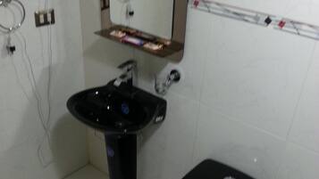 Un baño con inodoro negro, lavamanos y un espejo sobre otro espejo.