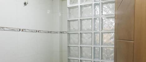 Un baño con inodoro, cabina de ducha de vidrio y lavamanos.