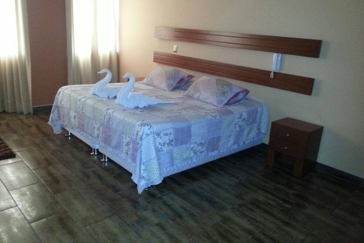 A neatly made bed with a floral bedspread and two decorative swans.