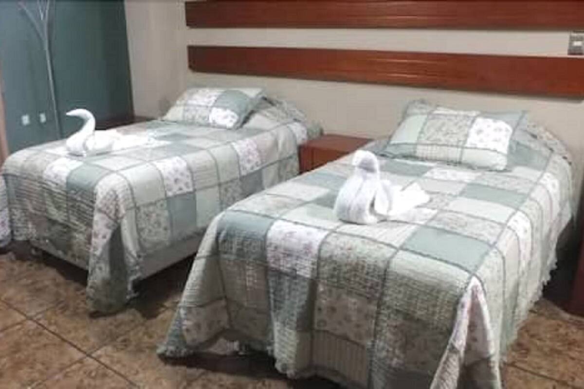 Two twin beds with floral bedding and decorative swans, a wooden headboard, and a tiled floor.