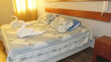A hotel room with a bed, wooden headboard, and a small red cabinet.