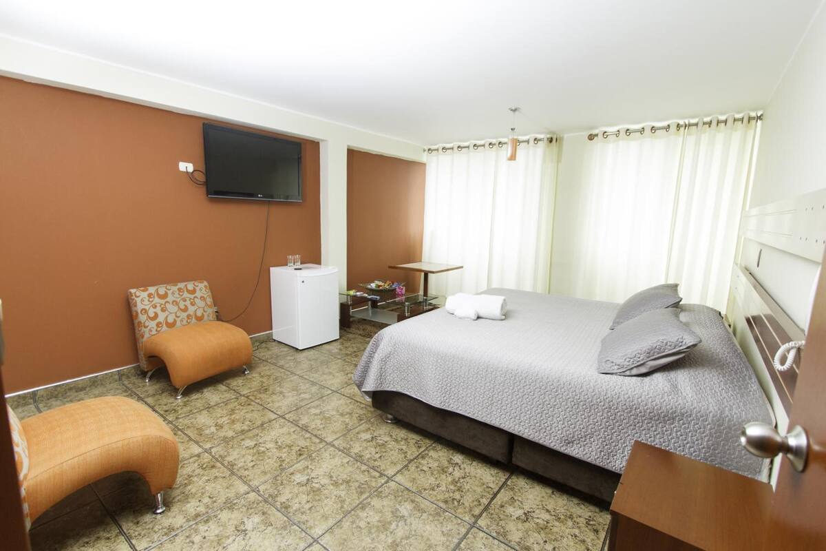A hotel room with a bed, a desk, a television, and a bathroom.