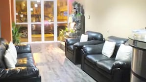 A lobby with leather sofas, a coffee table, and a large window with a view of the street outside.
