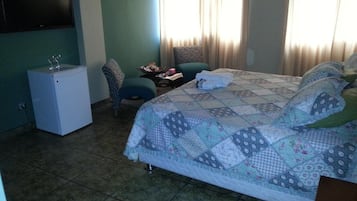 Un dormitorio con cama, un escritorio pequeño, una silla y televisión en la pared.