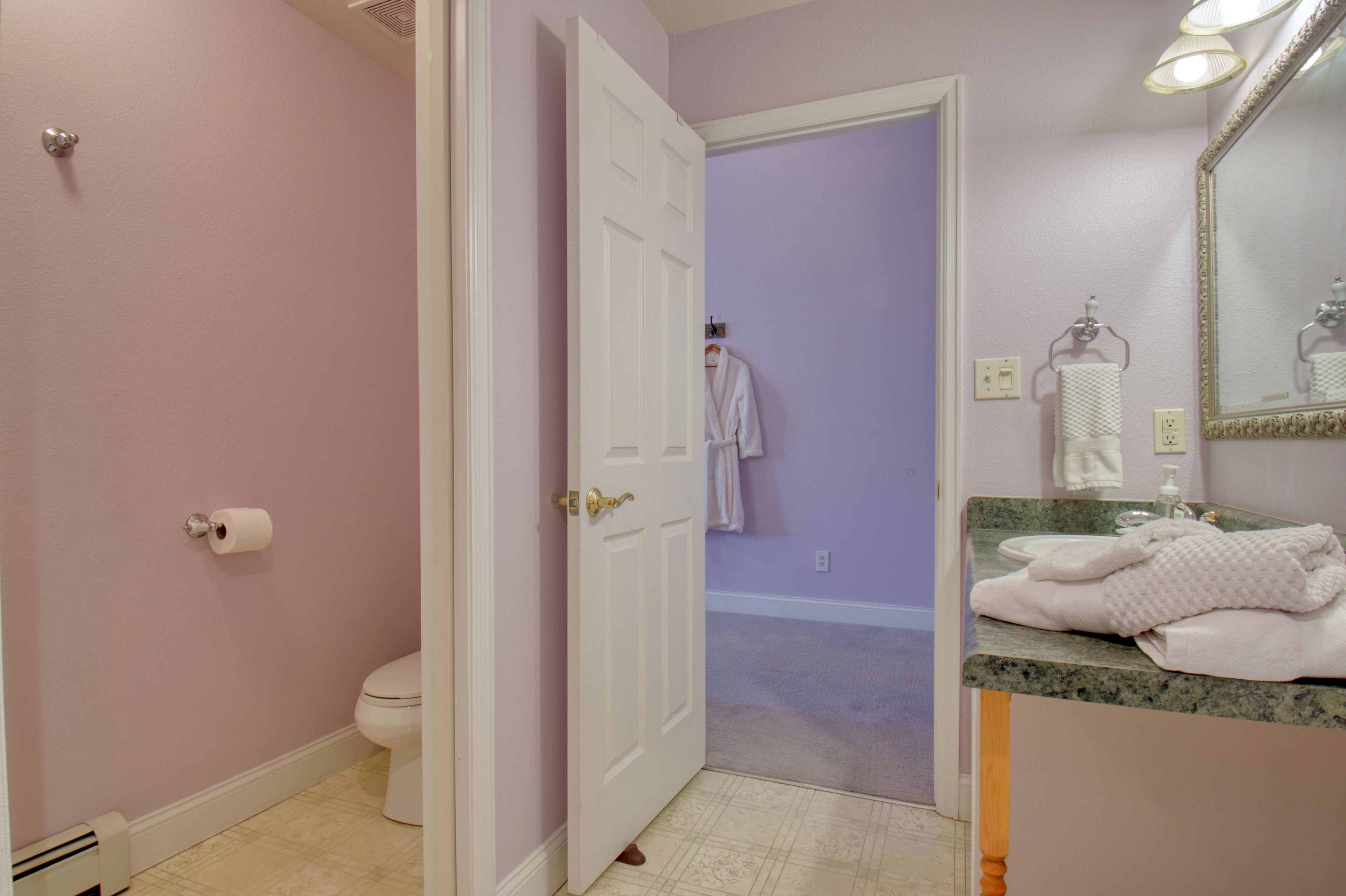 A bathroom with a toilet, a sink with a mirror, and a towel rack.