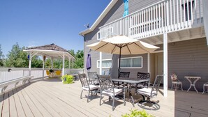 A covered outdoor deck with a gazebo, a dining table with chairs, and a patio umbrella. - Castle Creek B&B (Grand Junction)