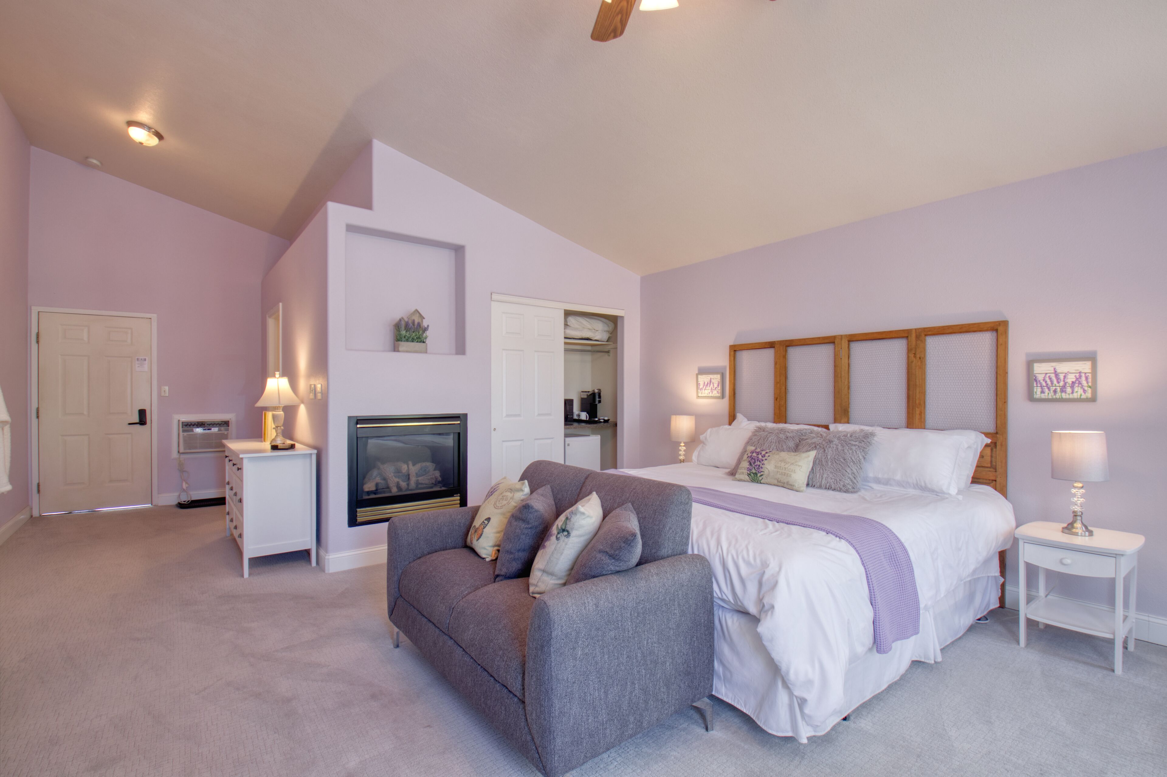 A bedroom with a bed, a sofa, a TV, a lamp, and a mirror.