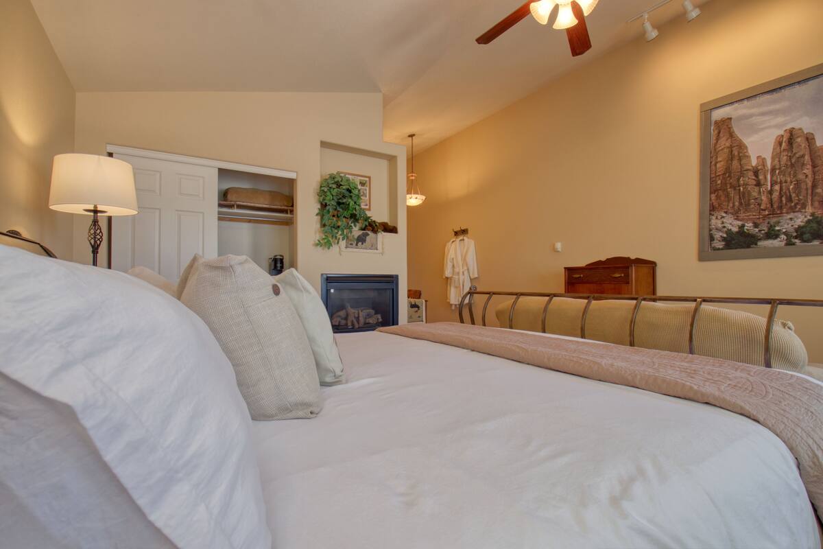A bedroom with a large bed, a dresser, a chair, and a painting on the wall.