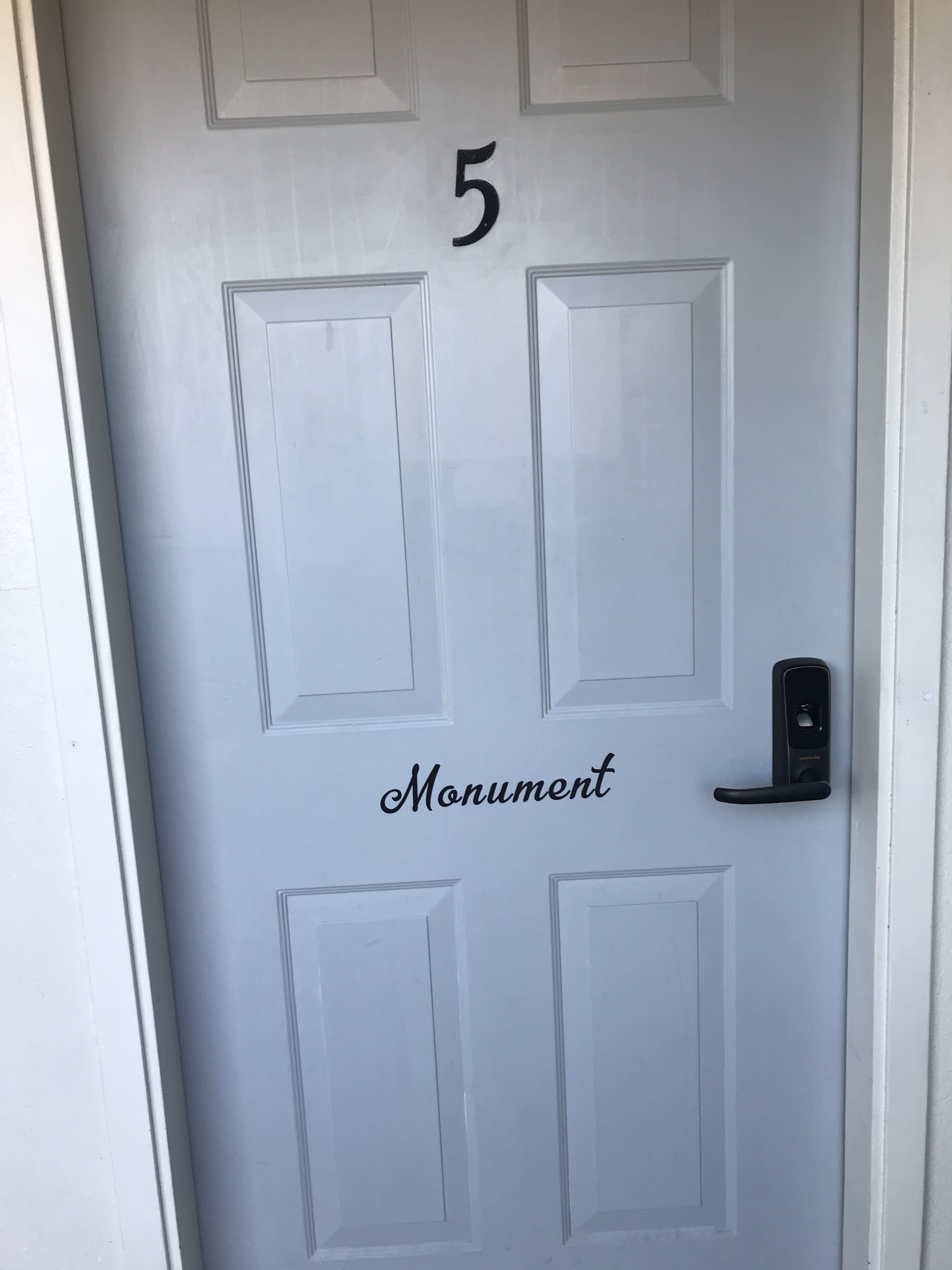 Une porte blanche portant le numéro 5 et le mot « Monument ».