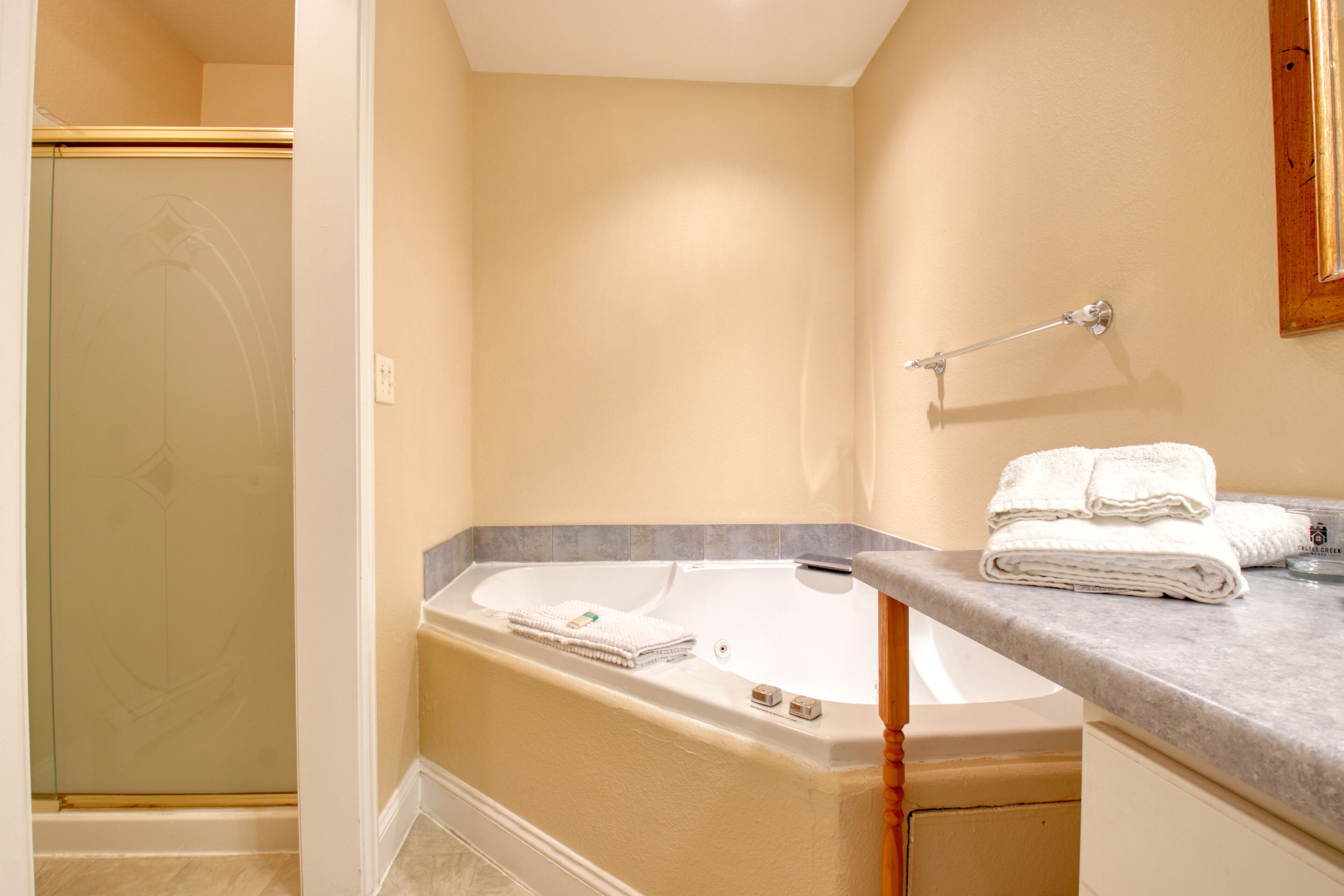A bathroom with a bathtub, a shower, and a vanity with towels.