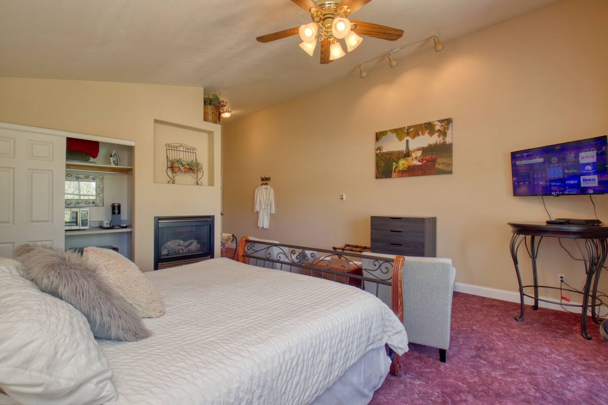 A bedroom with a bed, a desk, a chair, a television, and a ceiling fan.