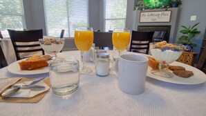 A breakfast setting with a table set for two, including plates with food, glasses of orange juice, a pitcher, and a mug. - Castle Creek B&B (Grand Junction)