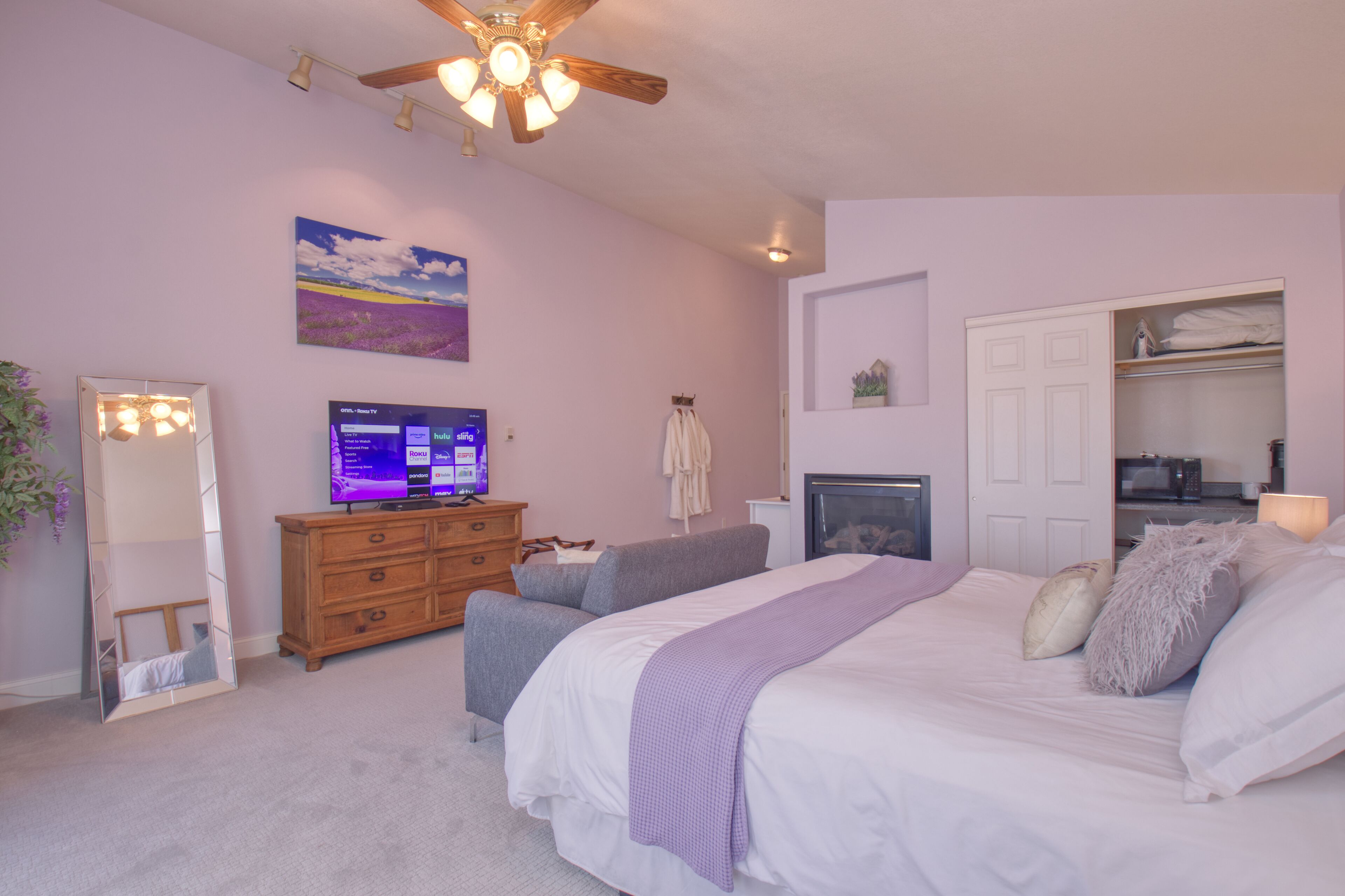 Une chambre à coucher comprenant un lit, une commode, un téléviseur, un ventilateur de plafond et un placard.