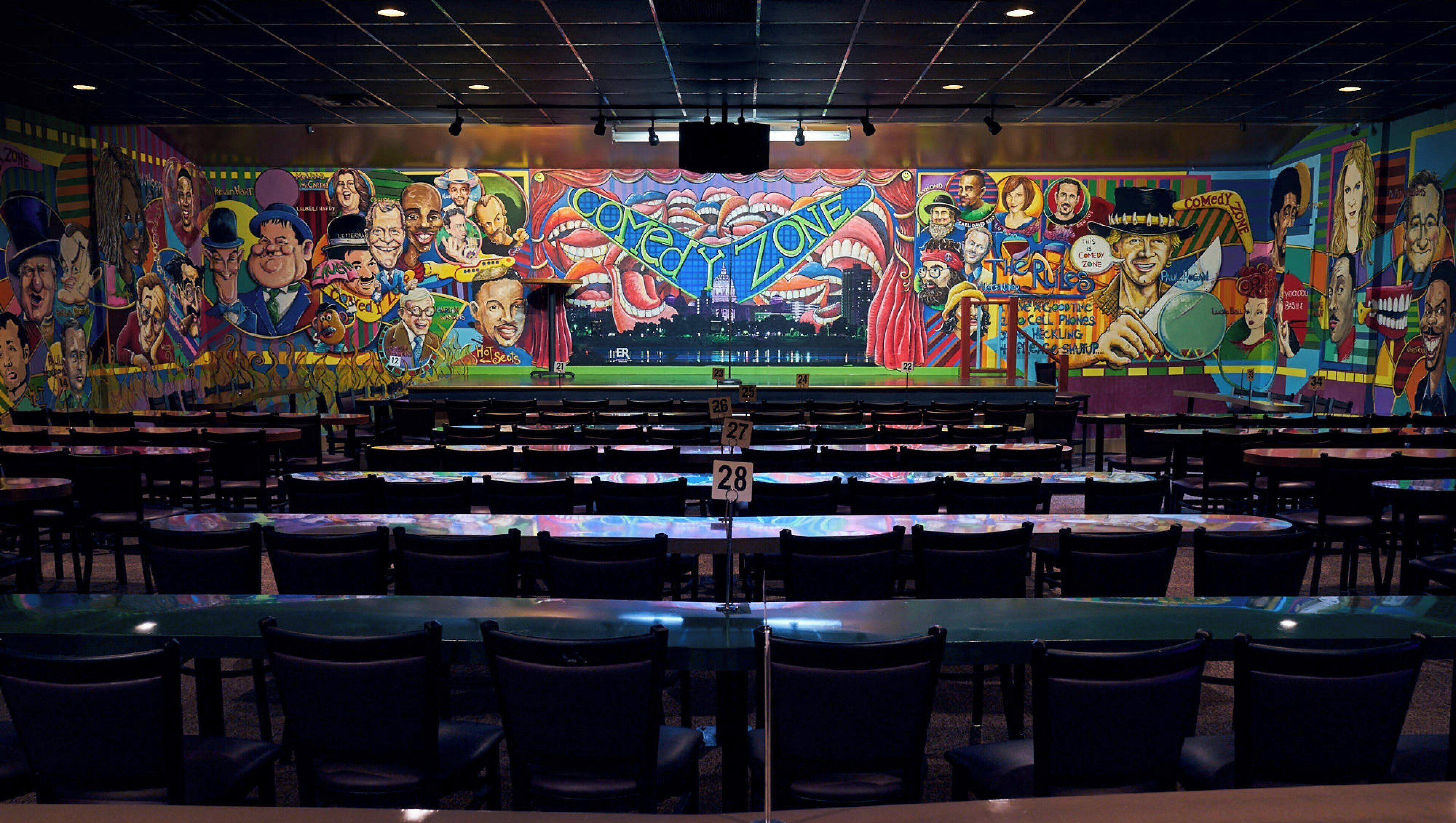 A restaurant with a large mural on the wall, multiple tables, and chairs arranged for dining.