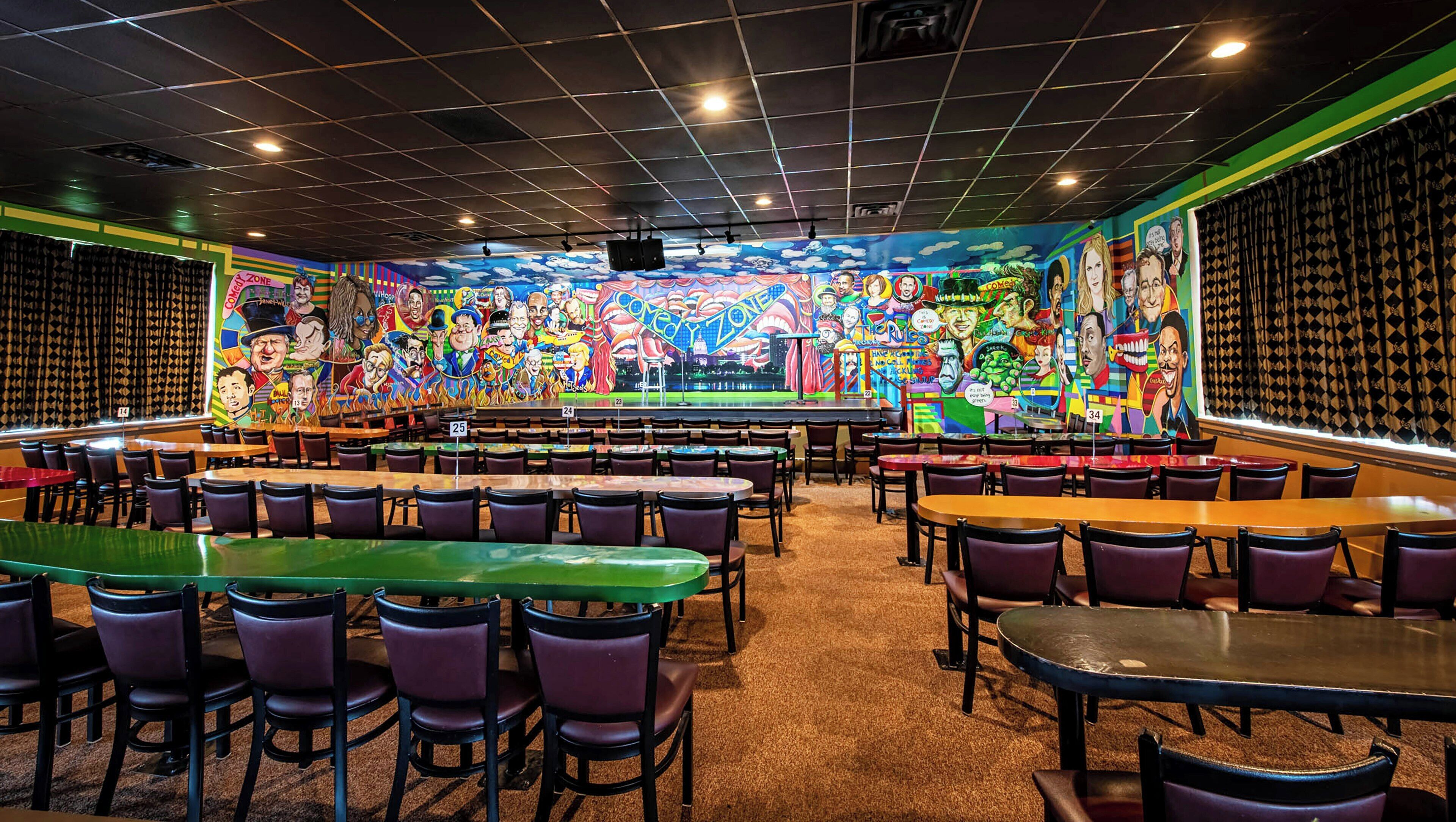 A restaurant with a vibrant mural, multiple dining tables, and chairs.
