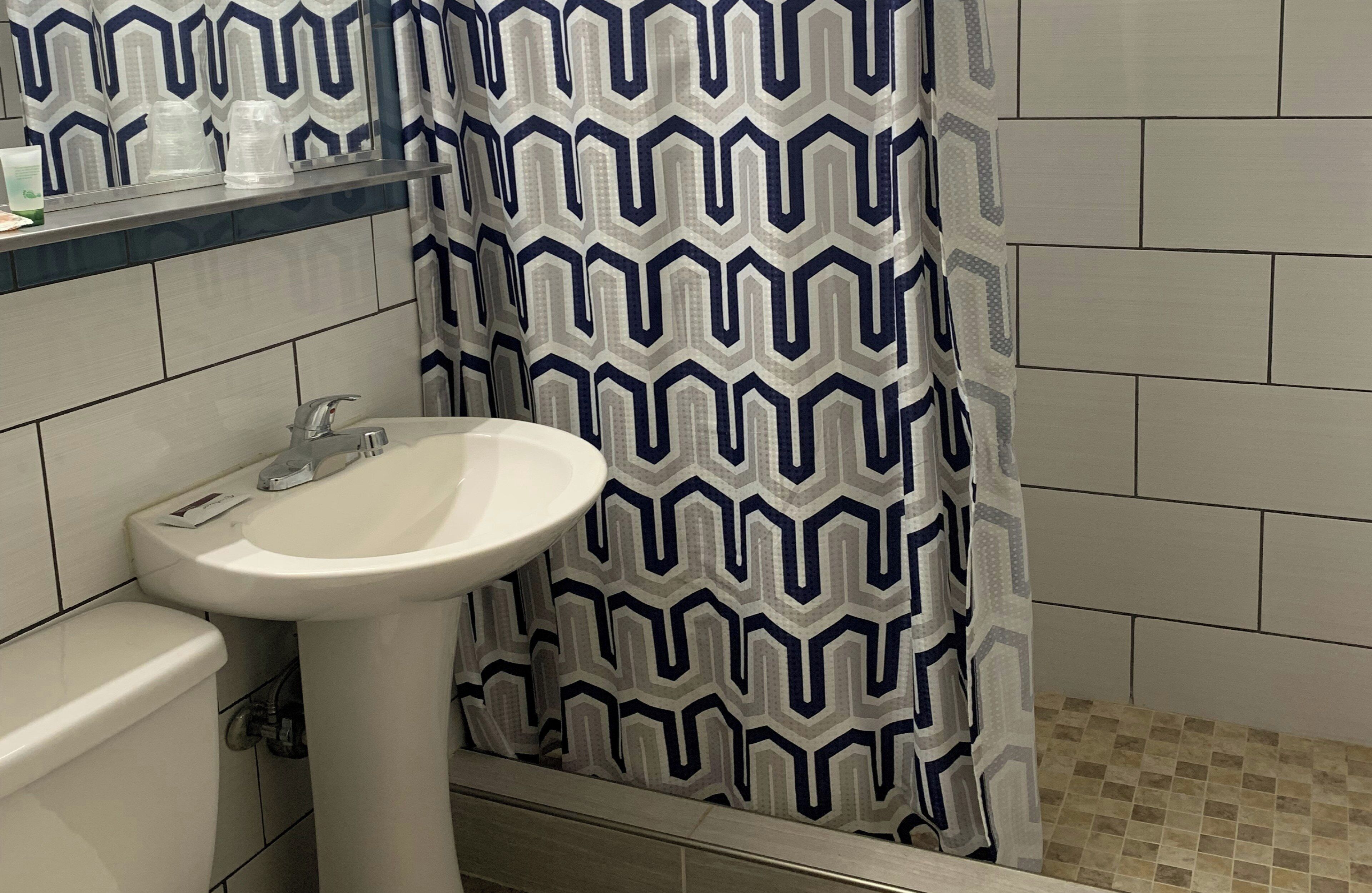 A bathroom with a white sink, a toilet, and a shower curtain with a geometric pattern.