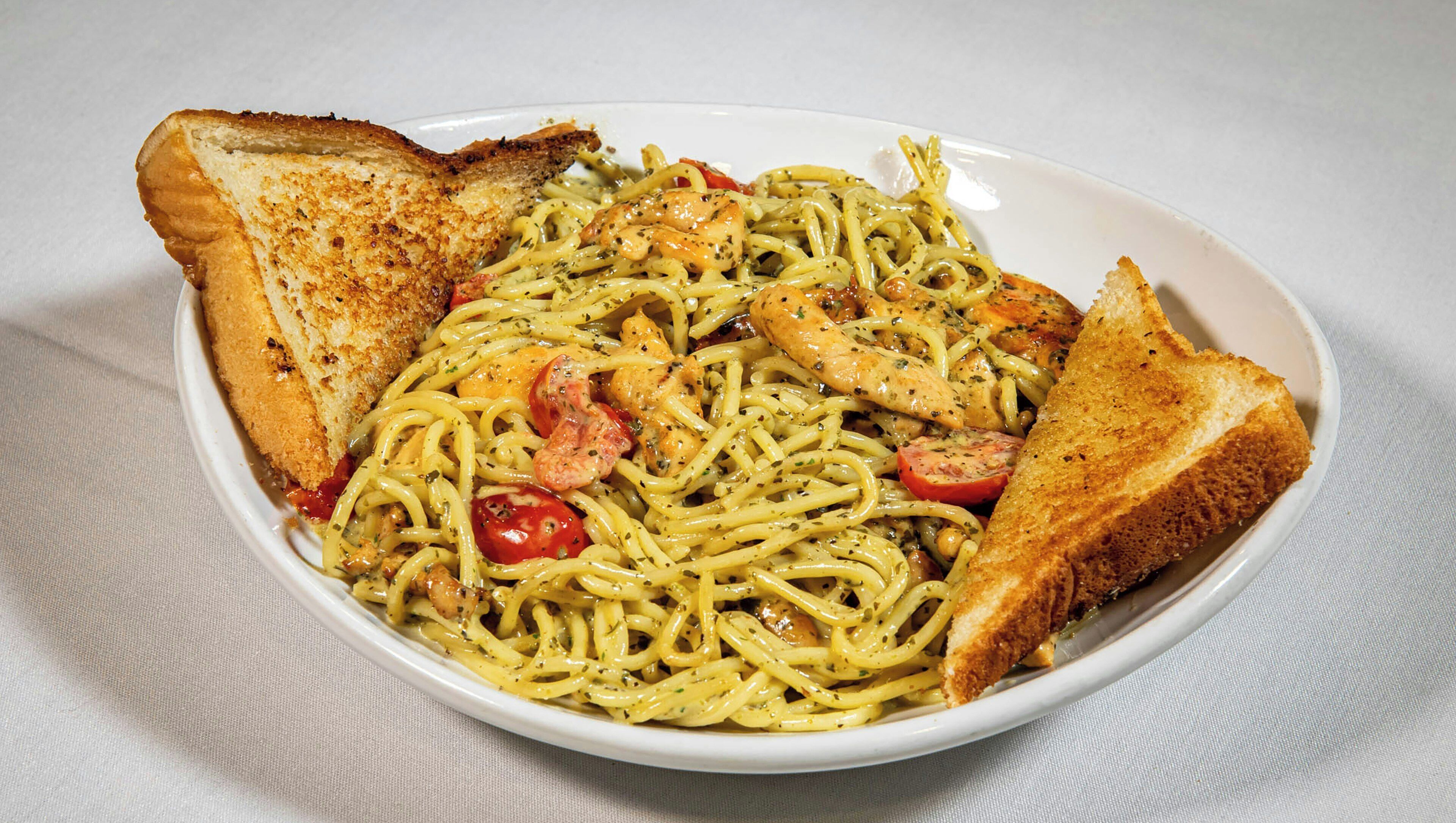 A bowl of spaghetti with tomatoes and bread.
